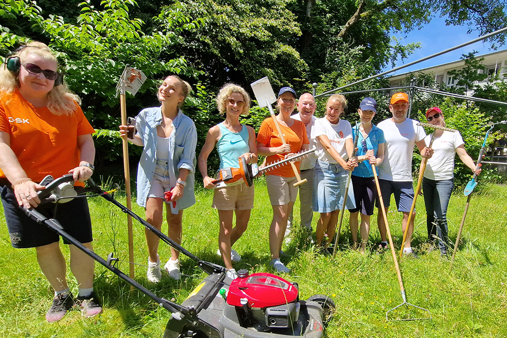 Gruppen an Personen mit Gartenarbeit-Utensilien in der Wiese.