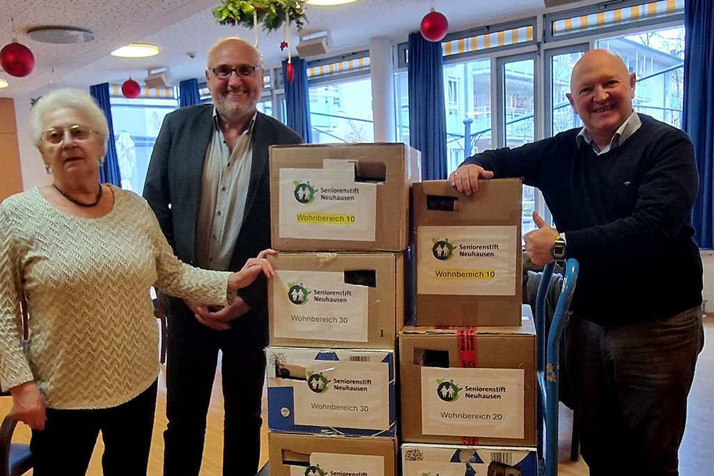 Drei Personen mit mehreren Paketen mit Aufschrift Seniorenstift Neuhausen Wohnbereich 10, 20 oder 30